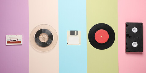 Floppy disk, vinyl record, film reel, vhs and audio cassette on a colored background. Retro 80s....