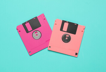 Pink floppy disks on blue background. Computer technology 80s. Top view.