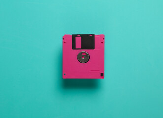 Pink floppy disk on blue background. Retro technology. Top view