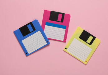Colored floppy disks on pink background. Retro technology. Top view