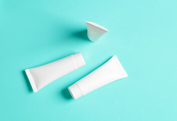 White cream tubes on a blue background. Mockup, template for design. Top view