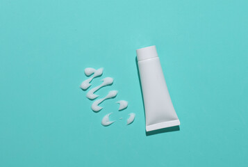 Mockup of a white tube with a smear of cream on blue background
