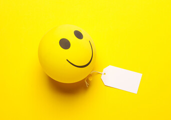Balloon with smile face and price tag on yellow background