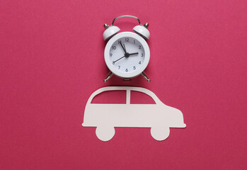 Paper cut car and alarm clock on pink background