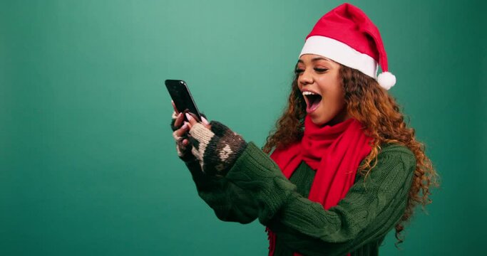 Beautiful young woman gets good news at Christmas, shocked excitement, studio