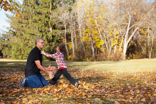 Grandfather and grandson playing in a park in autumn; Edmonton, alberta, canada