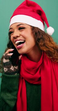 Happy young woman makes phone call talking and laughing at Christmas, studio