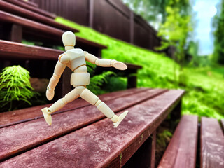 Wooden toy mannequin in the forest among grass and trees in summer, autumn, spring. The concept of outdoor recreation and hiking. Healthy lifestyle. Earth Day. Save planet concept. Partial focus, blur