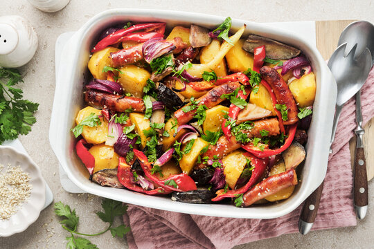 Baked sausage and vegetables, peppers, zucchini, tomatoes, red onion and eggplant with sesame and cilantro served hot from oven on baking tray. Traditional lunch dish BBQ. Sausage jersey tray bake.