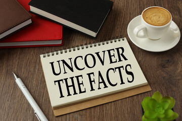 Uncover the facts. working environment with notepad and cup of coffee.words