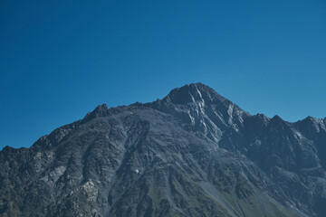 The Caucasus Mountains on the borders of Russia and Georgia. The village of Stepantsminda Kazbegi. Rocks and mountain peaks on a sunny warm summer day. Beautiful landscape.