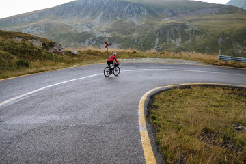 Female cyclist in bike packing tour.Bikepacking travel.Female cyclist is riding through foggy mountain landscape.Adventure cycling concept. Woman cycling in the nature.Transalpina road.Parâng Mountain