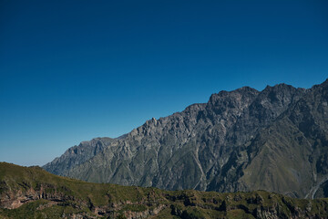 The Caucasus Mountains on the borders of Russia and Georgia. The village of Stepantsminda Kazbegi. Rocks and mountain peaks on a sunny warm summer day. Beautiful landscape.