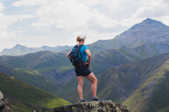 A Female Hiker Stands Looking Over The Landscape Of Mountains And Valleys; Yukon, Canada