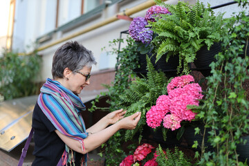 A female gardener in her floral shop, surrounded by beautiful plants and flowers, ready to assist customers.