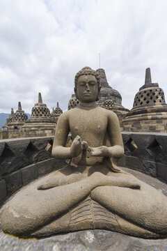 Buddha Statue With The Hand Position Of Dharmachakra Mudra Amidst The Latticed Stone Stupas Containing Buddha Statues On The Upper Terrace, Borobudur Temple Compounds, Central Java, Indonesia