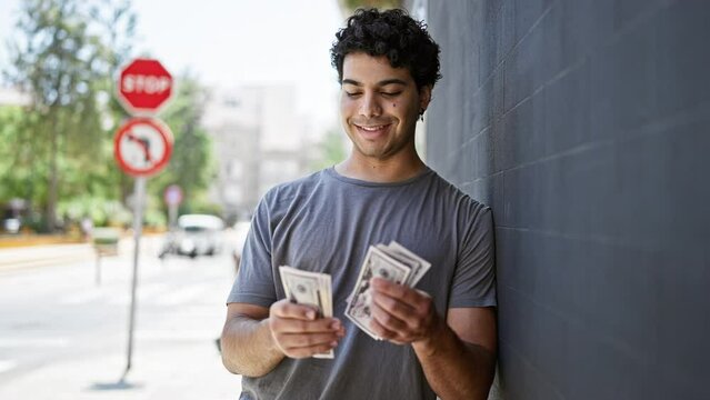 Young latin man smiling confident counting dollars at street