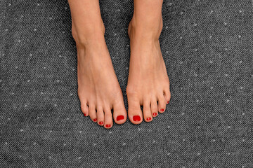 Female feet with red nails on black background closeup. Feet of a girl with fiery red nail polish...