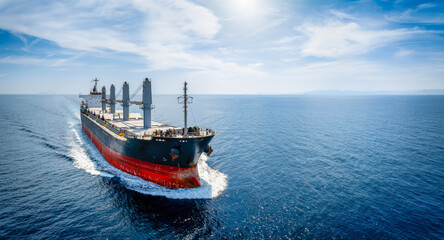 Aerial view of a bulk carrier cargo vessel traveling with high speed over blue sea