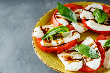 Yellow Plate of Healthy Classic Caprese Salad with Mozzarella Cheese, Tomatoes and Basil. Italian Cuisine