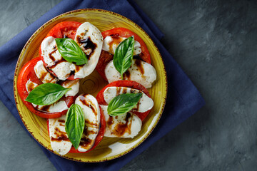 Yellow Plate of Healthy Classic Caprese Salad with Mozzarella Cheese, Tomatoes and Basil. Italian Cuisine