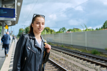 Young female waiting for an electric train at city railway station