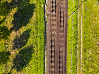 Eine Bahntrasse auf dem Land in der Sonne direkt von oben als Luftaufnahme