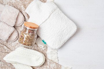 Fototapeta na wymiar Hot water bottle, infusion tea, warm socks for seasonal cold anf fast recovery. Self care during cold weather
