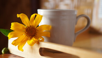 Yellow flower with cup of coffee or tea on the tray on the table. Morning coffee with fresh...