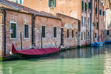 Fototapeta na wymiar Picturesque scene from Venice with a boat docked or moored on the narrow water canals.