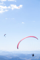 paragliders in the blue sky over the mountains
