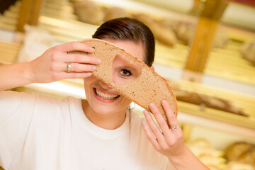 Bäckerin schaut durch Brotscheibe mit ausgeschnttenem Herz