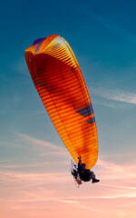 Powered hang glider against a blue sky.