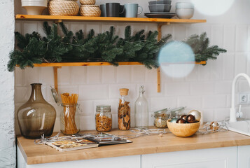 Christmas decor on the kitchen with garland. Festive home interior. Christmas tabletop setting over...
