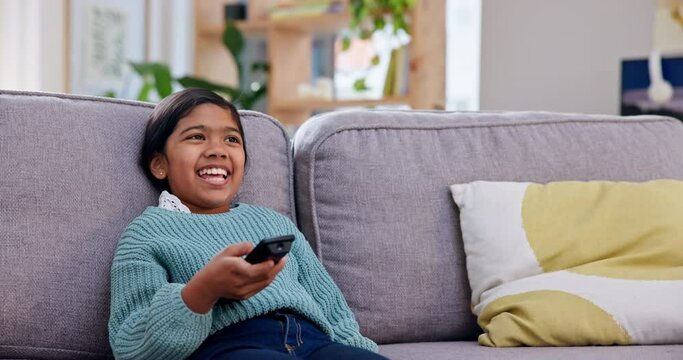 Girl child, remote and watching tv on sofa, click and smile with choice, excited and relax in family house. Female kid, happy and decision for cartoon, show or film on television or living room couch