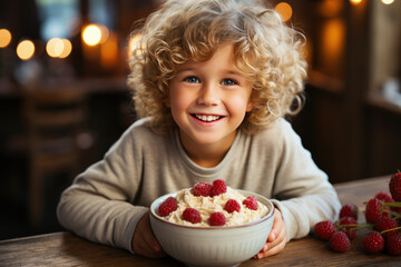 A smiling child is having breakfast with oatmeal porridge with berries - obrazy, fototapety, plakaty