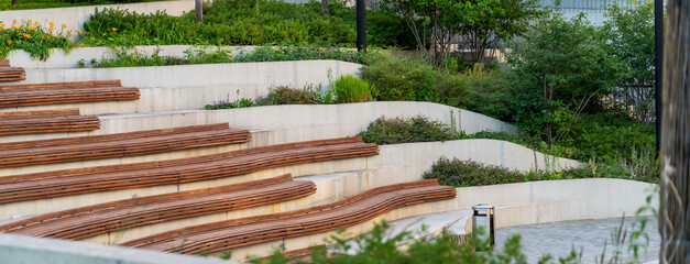 Curved concrete steps with wooden slats and flowers in the amphitheater in the city park