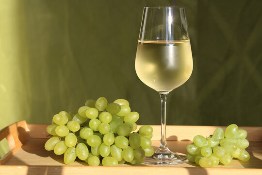 Glass of white wine on a tray with fresh grapes
