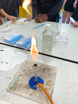 A Bunsen burner in a science lab in a school burning with a yellow flame.