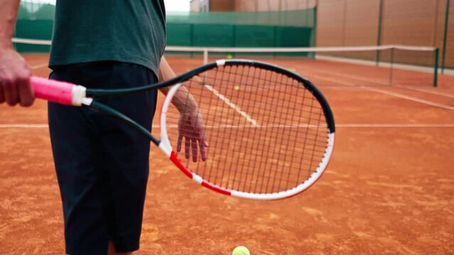 close-up  professional player coach on outdoor tennis court practices strokes with racket and tennis ball