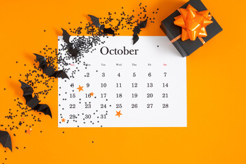 Halloween concept. October 2023 monthly calendar. Black Spiders, gift on yellow background. Halloween decor and decorations for holiday