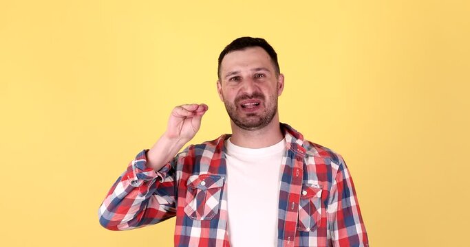 Irritated man showing bla-bla-bla gesture with hands on yellow background. Empty promises, blah concept. Lier.