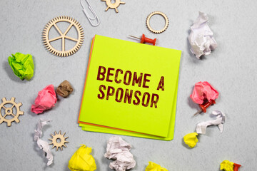Text become a sponsor on sticky notes with copy space and paper clip isolated on red background.