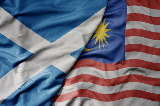 big waving national colorful flag of scotland and national flag of malaysia .