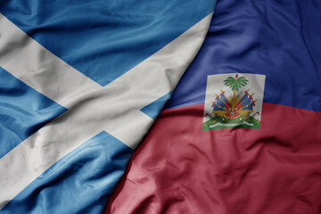 big waving national colorful flag of scotland and national flag of haiti .