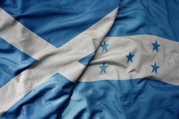 big waving national colorful flag of scotland and national flag of honduras .
