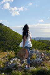 Latin woman in nature with straw hat looking at a mountain