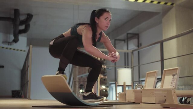 Girl exercising on balance board in fitness studio..
