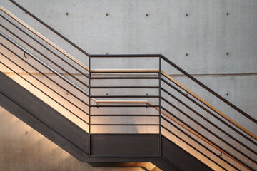 Interior front elevation view at the black steel staircase and background of modern loft concrete wall. - obrazy, fototapety, plakaty