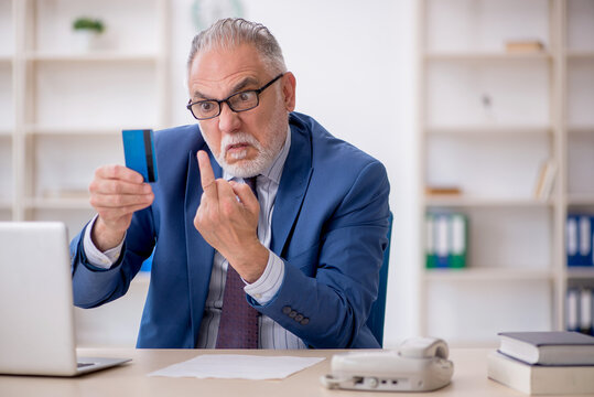 Old male employee holding credit card
